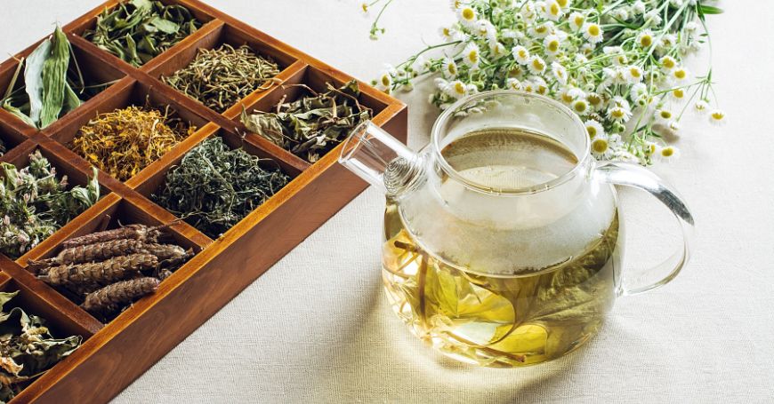 tea for colitis in a teapot with a tray of herbs